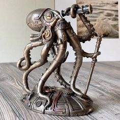 a statue of an alien holding a telescope on top of a wooden table next to pictures