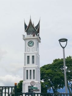 a tall white clock tower sitting next to a metal fence