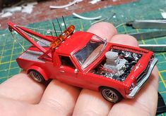 a hand holding a red toy truck on top of a table