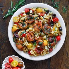 pasta salad with shrimp and cherry tomatoes in a white bowl on a wooden table top