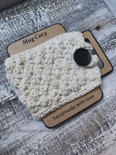 a white crocheted dish cloth with a black button on it sitting on top of a wooden table