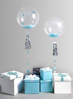 two balloons are suspended from the ceiling above boxes and presents in front of each other