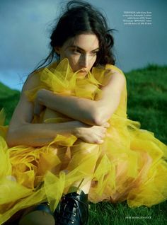 a woman in a yellow dress sitting on the grass