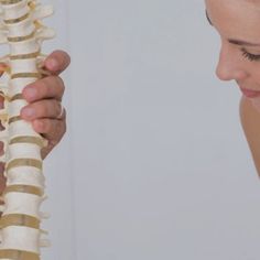 a woman is holding a bone in her right hand and looking at the bones on her left arm