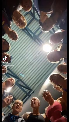 a group of people standing around each other in a circle looking up at the sky