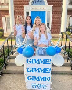 three girls are standing on the steps holding up signs and balloons that say gimme gimme