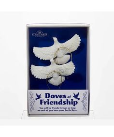 two white doves with hoop earrings in a cardboard box on a white background and the words doves of friendship written below them