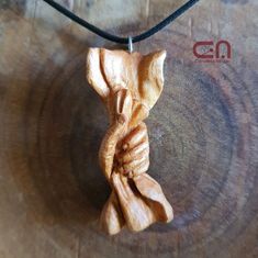 a wooden sculpture is hanging on a leather cord