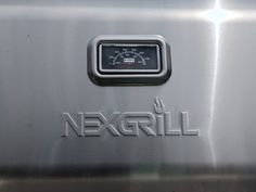 the word nexgrill is displayed on a stainless steel panel with a speedometer