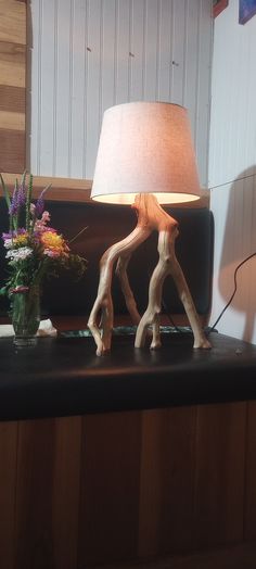 a table lamp sitting on top of a wooden shelf next to a vase filled with flowers