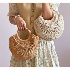 a woman holding two crocheted purses in her hands