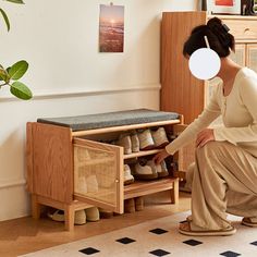 a woman kneeling down in front of a shoe rack