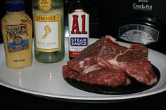 some meat is sitting on a plate next to bottles of alcohol and an electric pressure cooker