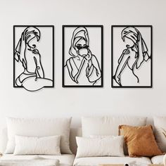 three black and white paintings on the wall above a couch