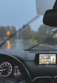 the dashboard of a car on a rainy day with rain and street lights in the distance