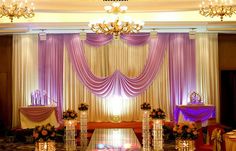 wedding stage decorated with purple drapes and chandeliers