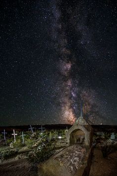 the night sky is filled with stars above a stone structure and crosses in front of it