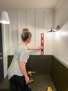 a woman is measuring the height of a wall with a tape measurer on it