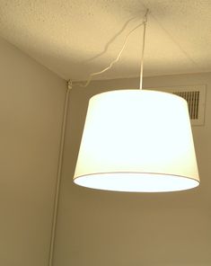 a white lamp hanging from the ceiling in a room next to a wall mounted air conditioner