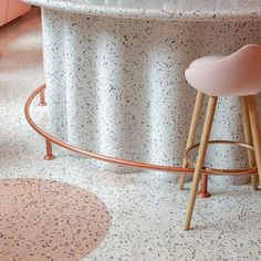 two pink stools sitting in front of a marble counter top with an oval rug