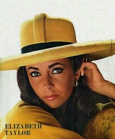 a woman wearing a yellow hat with her hand on her head and looking at the camera