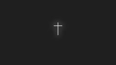 a white cross on a black background with only one light shining in the dark area