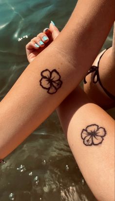 two people with tattoos on their arms sitting next to each other in the water and holding hands