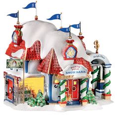 a small toy house with flags on the roof and snow on the ground around it