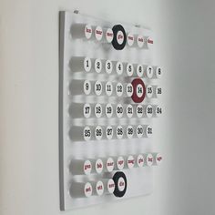 a white wall mounted calendar with numbers and magnets attached to the back of it