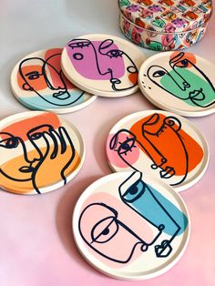 four plates with different designs on them sitting next to a bowl and container filled with candy