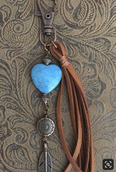 a key chain with a blue heart and feather charm hanging from it's side