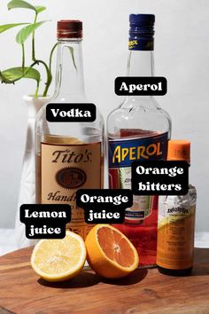 the ingredients for an alcoholic drink are displayed on a cutting board, including oranges, lemon juice and apricot