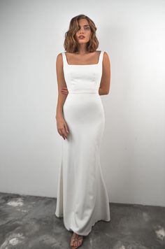 a woman in a white dress posing for the camera with her hands on her hips