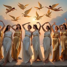 a group of women in white and gold dresses standing next to each other with birds flying above them