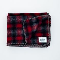 a red and black plaid blanket laying on top of a white surface