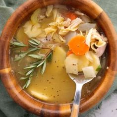 a wooden bowl filled with soup and vegetables