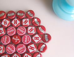 a bunch of red and white buttons sitting on top of a table next to a blue vase