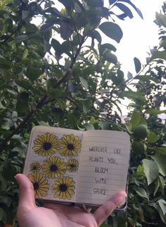 someone holding up an open notebook with flowers on it