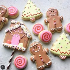 decorated gingerbreads and cookies are arranged on a white wooden table with a straw