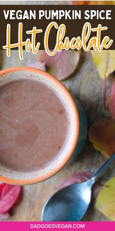 a close up of a cup of hot chocolate on a table with leaves and spoons