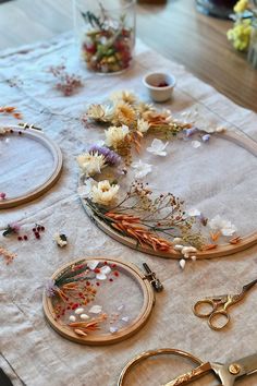 the table is covered with flowers and other crafting supplies, including embroidery hoops