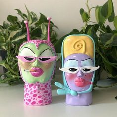 two toy figures are sitting next to each other on a table with plants in the background