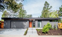 a modern house in the middle of a wooded area with trees and shrubs around it