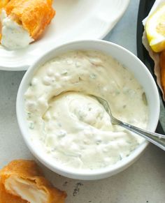 a white bowl filled with dip next to some fried food