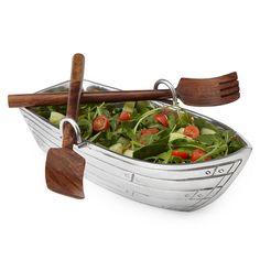 a salad in a boat with wooden utensils