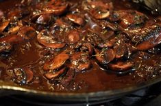 a pan filled with mushrooms and sauce on top of a stove