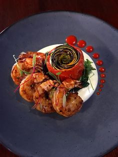 a blue plate topped with grilled shrimp next to tomatoes and garnishes