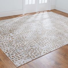 a white rug with brown spots on it in front of a door and wooden floor