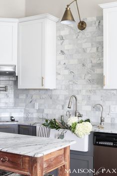 a kitchen with marble counter tops and white cabinets