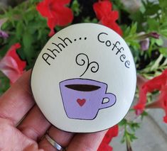 a hand holding a button with a cup of coffee on it and the words amh coffee